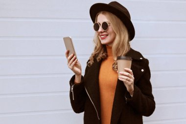 Yan görünüm portresi şık gülümseyen kadın akıllı telefona bakıyor.