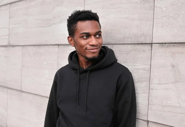 Porträtt leende ung afrikansk man bär svart luvtröja på stan — Stockfoto