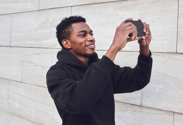 Jovem homem africano sorrindo tirando foto selfie por telefone na cidade — Fotografia de Stock