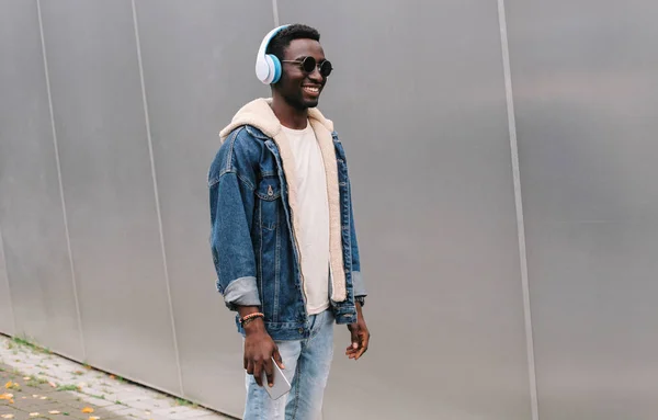 Cool hombre africano sonriente moderno en auriculares inalámbricos escuchando —  Fotos de Stock