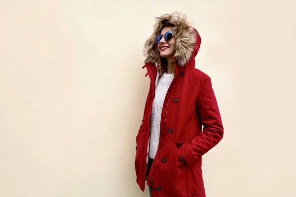 Vista lateral de la mujer sonriente con estilo en chaqueta roja con capucha de piel s — Foto de Stock
