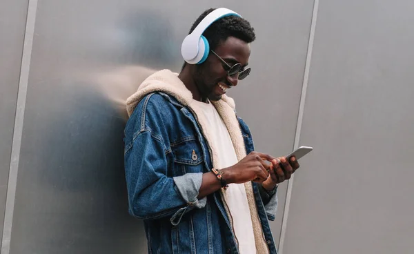 Cool modern smiling african man in wireless headphones listening