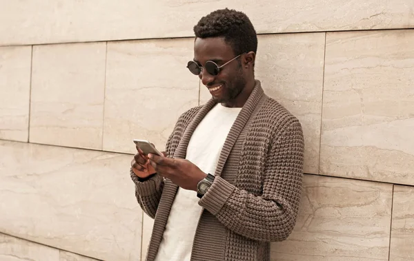 Portret szczęśliwy uśmiechnięty Afrykanin ze smartfonem noszącym brązowy — Zdjęcie stockowe