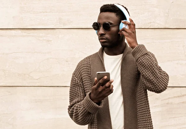 Portrait stylish african man with phone in wireless headphones l — ストック写真