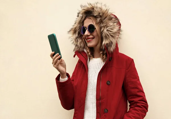 Retrato sonriente mujer joven sosteniendo teléfono con chaqueta roja wi —  Fotos de Stock