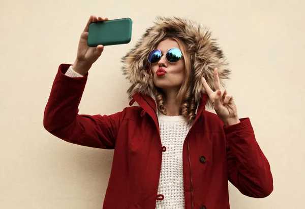 Havalı, genç bir kadın kırmızı dudaklarını silip selfie çekiyor. — Stok fotoğraf