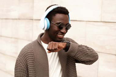 Akıllı akıllı Afrikalı bir adam sesli komut kaydedici kullanıyor ya da şehir sokaklarında müzik dinleyen kablosuz kulaklıklar takıyor.