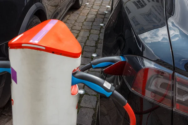 The power supply plugged into an electric car during charging in Copenhagen. Close up Electric car charging station.