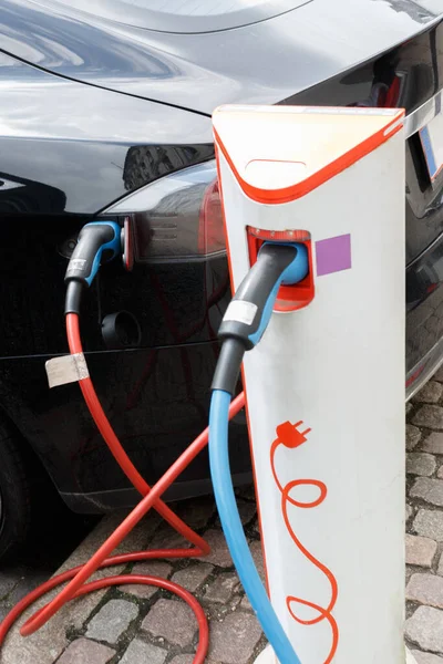 The power supply plugged into an electric car during charging in Copenhagen. Close up Electric car charging station.