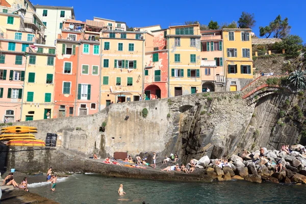 Cinque Terre aldeia Riomaggiore com casas coloridas e pessoas tomando banho, Itália — Fotografia de Stock
