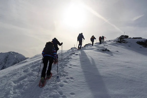 Group of people hiking on snowshoes and mountain snow panorama with summit cross in Stubai Alps, Austria — Stock Photo, Image