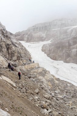 İtalya 'nın Brenta Dolomites dağlarındaki kar tarlasında Bocca del Tuckett Yolu' na doğru yürüyüş yapan insanlar