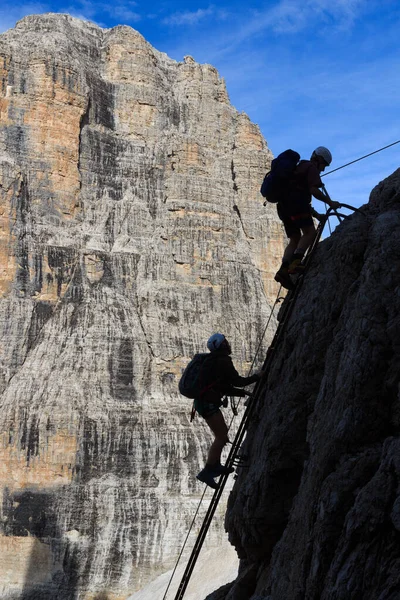 Man and woman climbing a ladder on Via Ferrata Sentiero Brentari in Brenta Dolomites mountains, Italy