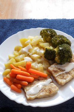 brokoli, Balık dosya, havuç ve patates beyaz tabak mavi arka plan dikey görünüm