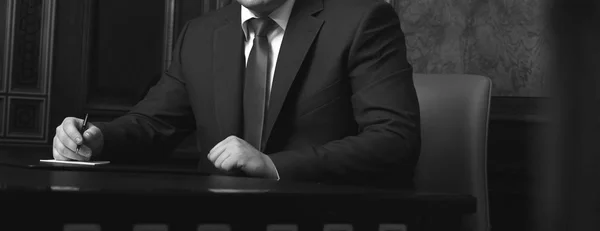 Närbild av affärsmannen sitter vid bord och underteckna dokument, svartvit foto — Stockfoto