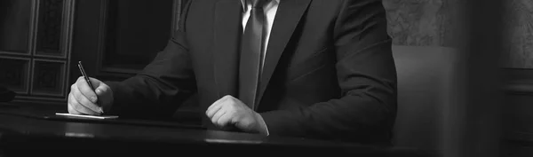 Close up van zakenman zittend aan tafel en ondertekening document, zwart-wit foto Stockfoto