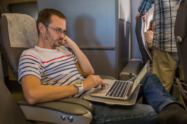 Uçak kabin içinde laptop üstünde onun seyahat sırasında çalışan adam