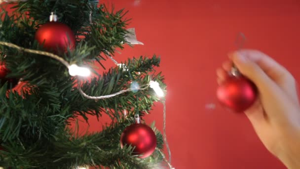 Mädchen schmückt Weihnachtsbaum mit rotem Spielzeug — Stockvideo