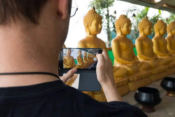 Hombre tomando fotos de una fila de estatua de buda dorada en Phuket —  Fotos de Stock