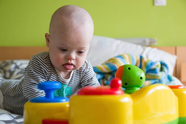Cute baby boy with Down syndrome playing with toy — Stock Photo, Image