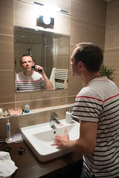 Handsome man shaving in the mirror in the bathroom