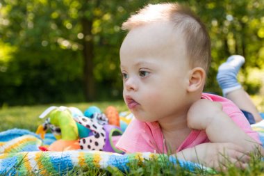 Şirin bebek çocuk Down sendromlu bir battaniye var yaz günü doğa içinde yatan portresi