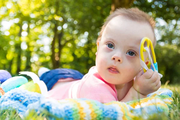 Portrait of Cute baby boy with Down syndrome lying on blanket in summer day on nature — Stock Photo, Image