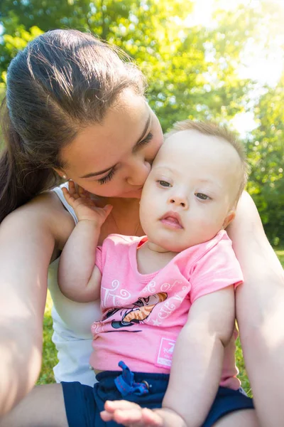 Cute baby boy with Down syndrome and his young mother in summer day — Stock Photo, Image