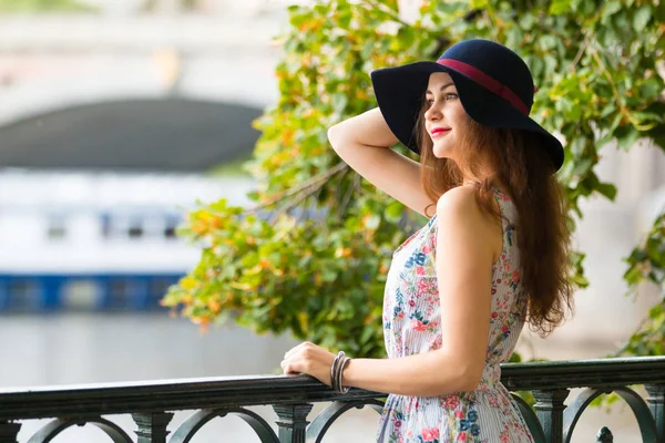 Ritratto della bella ragazza alla moda con cappello su argine in giorno estivo — Foto Stock