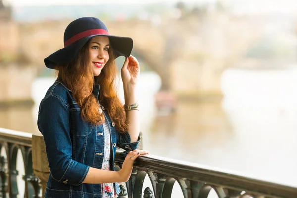 Portrait of the beautiful fashionable girl with hat on embankment in summer day — Stock Photo, Image