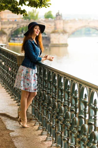 Portrait of the beautiful fashionable girl with hat on embankment in summer day — Stock Photo, Image