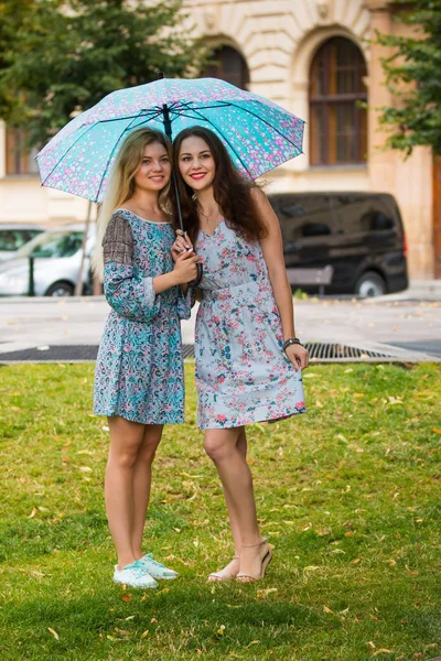 Portrait of two happy women with umbrella in street — Stock Photo, Image