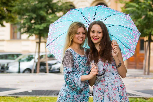 Портрет двух счастливых женщин с зонтиком на улице — стоковое фото
