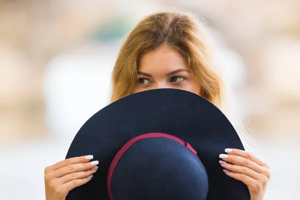 Portrait of the beautiful fashionable girl playing with hat outdoor — Stock Photo, Image