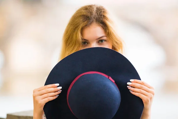 Портрет красивой модной девушки, играющей со шляпой на открытом воздухе — стоковое фото