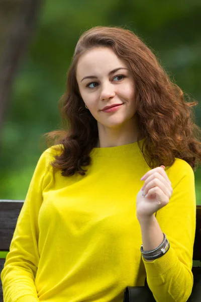 Retrato de la hermosa chica de moda en el banco en el parque — Foto de Stock