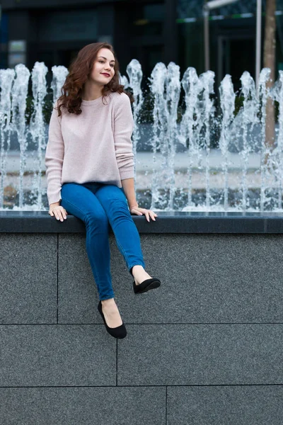 Sevimli genç kadın yanındaki çeşme Caddesi kentin üzerinde eğleniyor