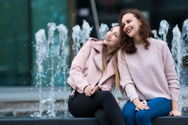 Deux belles jeunes femmes s'amusent à côté de la fontaine sur la rue de la ville — Photo