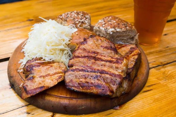 Izgara domuz eti ile bira, sarımsak daldırma, ekşi lahana
