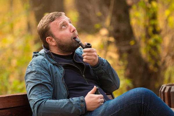 若い男は公園での喫煙パイプを吸う — ストック写真