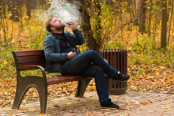 Ung man röker tobak pipe i park — Stockfoto