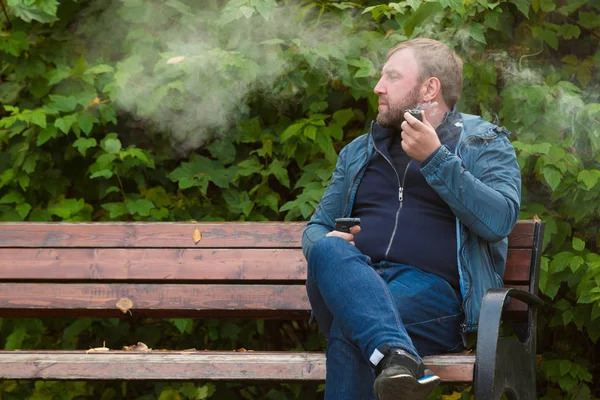 Ung man röker tobak pipe i park — Stockfoto