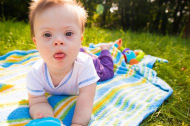 Şirin bebek çocuk Down sendromlu bir battaniye var yaz günü doğa içinde yatan portresi