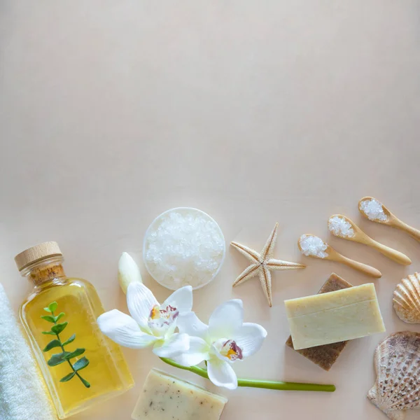 Vista superior del entorno Wellness. Sal marina, jabón, toalla, aceite de oliva y flores sobre fondo de madera — Foto de Stock