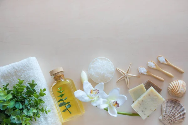 Vista superior del entorno Wellness. Sal marina, jabón, toalla, aceite de oliva y flores sobre fondo de madera — Foto de Stock