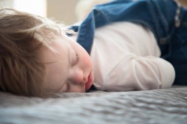 Down sendromlu yatakta uyuyan sevimli bebek