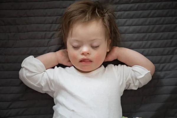 Carino bambino con sindrome di Down dormire sul letto — Foto Stock