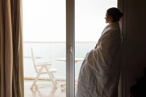 Womanin 白色毯子的剪影看窗外在家 — 图库照片
