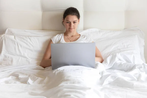 Retrato chica bastante joven con ordenador portátil en la cama por la mañana —  Fotos de Stock