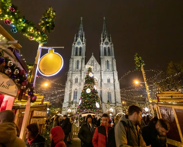 Praag, Tsjechië - 25.11.2019: Kerst kermis en versierde kerstboom op Namesti Miru plein tegen de bouw van de St. Ludmila kerk, Praag, Tsjechië — Stockfoto